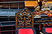 Detail of a gondola in Venice, Italy, showing a painted chair and brass merman.