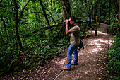 George of the Cloud Forest, guide and specialist, using binoculars to spot wildlife in Monterey cloud forest during fauna tour, Costa Rica