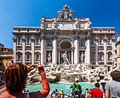 Rom,Italien,22. Juli 2017,Touristen fotografieren begeistert den atemberaubenden Trevi-Brunnen in Rom und genießen die lebhafte Atmosphäre unter einem strahlend blauen Himmel.