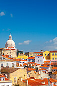 Explore the charming streets of Lisbon with the dome of Santa Engracia church rising above colorful rooftops on a clear day.