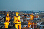 A beautiful aerial view of the 18th century San Ildefonso Church in Seville, Spain, showcasing its stunning baroque architecture illuminated against the urban skyline.