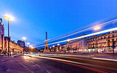 Light trails from passing traffic illuminate Restauradores Square, showcasing the obelisk at dusk in the heart of Lisbon.