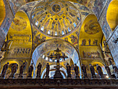 The silver and bronze crucifix on the Gothic altar screen in St. Mark's Basilica in Venice, Italy. On either side are statues of the Virgin and the Twelve Apostles.