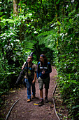 George of the Cloud Forest, guide and specialist, guides a young woman through Monterey cloud forest during fauna tour, Costa Rica