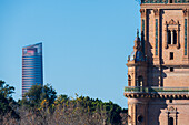 Scenic view of the Plaza de Espana tower with the modern Torre Sevilla in the background, surrounded by lush greenery in Seville, Spain, showcasing architectural contrasts.