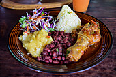 Casado dish with rice, chicken and peas, and fruit juice on table.