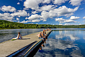 A group of people relaxing on a sunny day at Sognsvann Lake, Oslo, Norway, enjoying the serene summer scenery and calm waters.