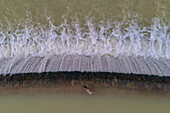 Luftaufnahme eines Vogels,der sich neben einem kleinen Wasserfall in einem künstlichen See ausruht