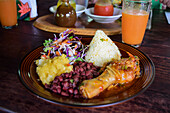 Casado dish with rice, chicken and peas, and fruit juice on table.