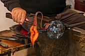 The glassblower shapes the pitcher handle in a glassblowing demonstration in Venice, Italy.