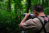 George of the Cloud Forest, guide and specialist, using a spotting scope in Monterey cloud forest during fauna tour, Costa Rica