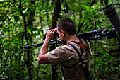 George of the Cloud Forest, guide and specialist, using binoculars to spot wildlife in Monterey cloud forest during fauna tour, Costa Rica