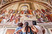 Rome, Italy, July 22 2017, A group of visitors marvels at Raphael's School of Athens in the Vatican Museums, exploring the masterpiece in Rome, Italy.