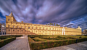 The Hospital de las Cinco Llagas, now the Andalusian Parliament, stands majestically under dramatic skies in Seville, Spain. This 16th-century architectural masterpiece is surrounded by lush gardens and historic charm.