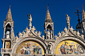 Gothic towers & statues on the west facade of St. Mark's Basilica in Venice, Italy. The mosaics depict scenes from the life of Christ.