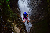 Young caucasian woman canyoning and rappelling in Costa Rica