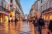 Lisbon, Portugal, March 1 2007, Pedestrians enjoy a leisurely walk along Augusta Street as dusk falls over Lisbon's bustling Baixa district, filled with charming shops.