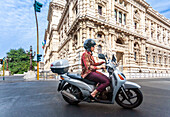 Rome, Italy, July 22 2017, Woman smokes while riding a scooter near The Supreme Court of Cassation.