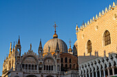 Golden light on the south facade of St. Mark's Basilica with the Doge's Palace at right, in Venice, Italy.