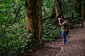 George of the Cloud Forest, guide and specialist, using binoculars to spot wildlife in Monterey cloud forest during fauna tour, Costa Rica