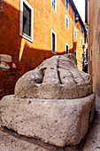 A massive foot of a historic Roman statue rests alongside a street in bustling Rome, showcasing ancient artistry and culture.