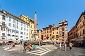 Rome, Italy, July 2017, Tourists and locals relax near an ancient fountain in Rome's historic square.