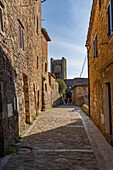 A narrow cobblestone street in the medieval walled town of Monteriggioni, Sienna Province, Italy.