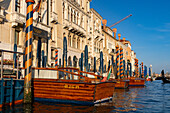 Classic wooden motorboat water taxis moored in front of luxury hotels on the Grand Canal, Venice, Italy.