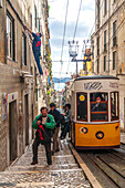 Lisbon, Portugal, March 1 2007, A man is climbing a ladder adjacent to Lisbon's Elevador da Bica, with people strolling along the charming streets below.