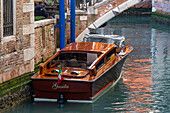 A classic wooden motorboat water taxi in a canal in Venice, Italy.