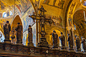 The silver and bronze crucifix on the Gothic altar screen in St. Mark's Basilica in Venice, Italy. On either side are statues of the Virgin and the Twelve Apostles.