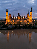 Aerial view of an illuminated El Pilar Basilica Cathedral and the Ebro River at night, Zaragoza, Spain