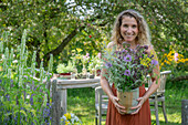 Woman holding a bouquet of flowers with fennel, oregano and mint in the garden