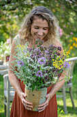 Woman holding a bouquet of flowers with fennel, oregano and mint