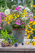 Summer bouquet of wild carrot, ornamental basket, globe thistle, fennel blossoms, scented nettle, dyer's chamomile in vase on garden table