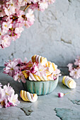 Arrangement mit pastellfarbenen Marshmallows und Frühlingsblüten