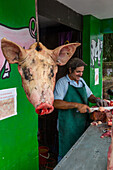 Butcher cutting up pig at open-air butcher shop