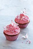 Pink cupcakes with butterfly decoration and sugar pearls