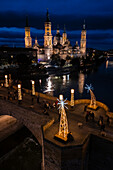 Aerial view of the Cathedral Basilica of Our Lady of the Pillar and Stone Bridge illuminated at night during Christmas, Zaragoza, Spain