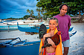 A tourist girl with a chicken and a local fisher in white sand beach in of Langub Beach Malapascua island, Cebu, Philippines