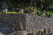 Large, colorful ceramic pots on a stone wall at a ceramic shop on the Amalfi Coast of Italy.