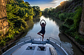 Doing yoga in a boat in the Canal du Midi near Carcassonne Aude South of France southern waterway waterways holidaymakers queue for a boat trip on the river, France, Europe