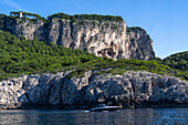 A powerboat passes beneath an old watchtower on the cliffs on the west coast of Capri, Italy. Towers and forts were built starting in the 9th Century to protect the island from raids by Saracen pirates.