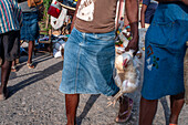 Girl selling a chicken in a local market and houses in the historic colonial old town, Jacmel city center, Haiti, West Indies, Caribbean, Central America