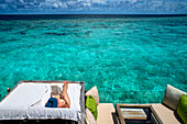 Relaxing reading a book nude in the luxury ower water villas of Six Senses Laamu maldives luxury resort villas, Laamu Atoll region Maldives