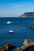 Fischerboote vor der zerklüfteten Küste der Stadt Manarola in den Cinque Terre, Italien.