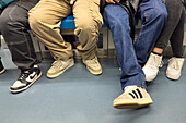 Legs and feet of young passengers on a metro train in Naples, Italy.