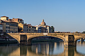 Ponte Santa Trinita or Holy Trinity Bridge across the Arno River in Florence, Italy. Behind is the dome of the Church of San Frediano in Cestello.