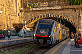 The Trenitalia Rock passenger train exits a tunnel at the station in Riomaggiore, Italy.