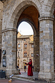 An actor in costume imitates Dante on the street in the medieval walled town of San Gimignano, Italy.